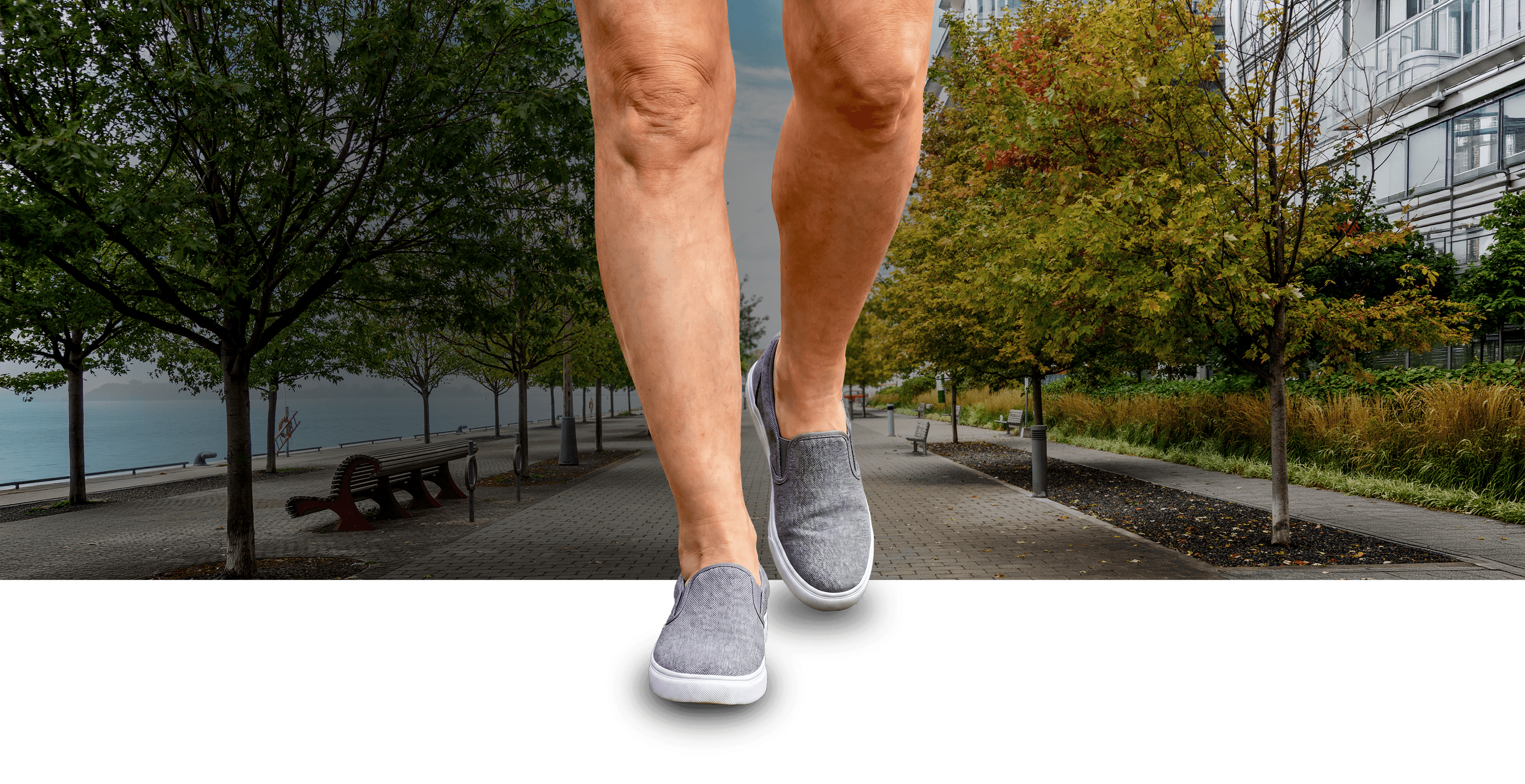 A disproportionately large pair of legs, visible from mid-thigh down, walking down a sidewalk.